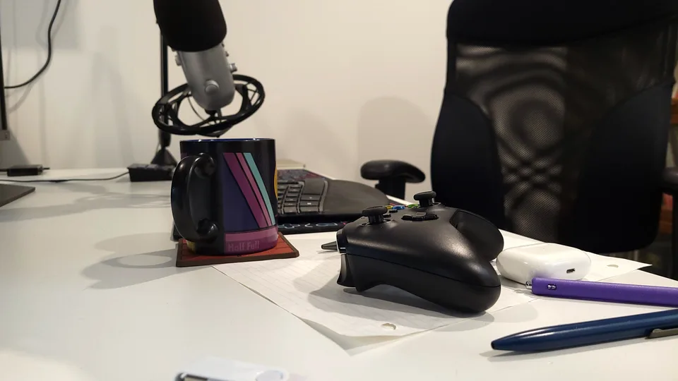 A game controller beside a cup of coffee on a desk